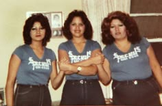 three women in blue shirts standing next to each other with their arms crossed and looking at the camera