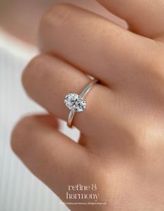 a woman's hand with a diamond ring on top of her finger and the words refine & harmony written below it