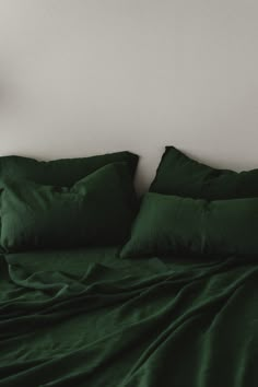 a bed with green sheets and pillows on top of it next to a wall clock