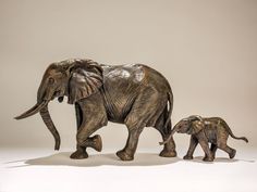 an adult and baby elephant walking next to each other in front of a white background