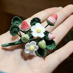 small crocheted flowers are placed on the palm of a person's hand