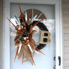 a wreath with the letter b is hanging on a front door decorated with halloween decorations