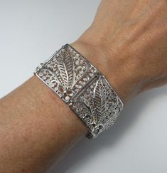 Here is an exceptional Art Nouveau completely handmade silver filigree bracelet circa 1890. The workmanship here is reminiscent of 18th century filigree in the quality and intricacy of this amazing piece. Each panel is entirely made by hand with silver wire twisted and wound into a fern and frond design each bouquet tied with a feminine bow. Amazingly each panel is not flat but the silver lace design is raised in relief with the central fern frond sitting higher to the rest of the panel. When th Victorian Cuff Bracelet With Intricate Design For Ceremonial, Victorian Cuff Bracelet With Intricate Design For Ceremonial Occasions, Victorian Style Ceremonial Cuff Bracelet With Intricate Design, Victorian Bangle With Intricate Design For Ceremonial Occasions, Elegant Ceremonial Engraved Cuff Bracelet, Elegant Engraved Ceremonial Cuff Bracelet, Elegant Engraved Cuff Bracelet For Ceremonial Occasions, Elegant Cuff Bracelet With Intricate Design For Formal Events, Elegant Cuff Bracelet With Intricate Design For Formal Occasions