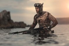 a man in wetsuit paddling his kayak on the water at sunset or dawn