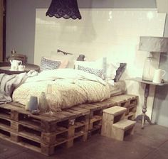 a bed made out of wooden pallets with pillows and blankets on top of it