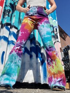 a woman standing in front of a building with her hands on her hips wearing colorful pants