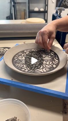 a person is making a decorative plate on a table