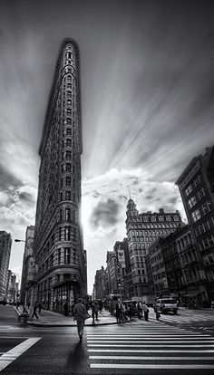 a black and white photo of people crossing the street in front of a tall building