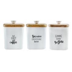 three ceramic canisters with wooden lids and sayings on the front, one is white