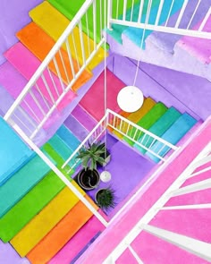 an overhead view of a colorful staircase with potted plants on the bottom and rainbow painted walls