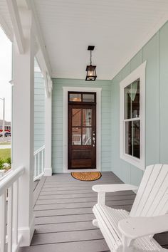 a white chair sitting on top of a porch next to a wooden door and window