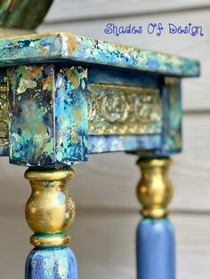 a blue and gold painted table sitting on top of a wooden floor