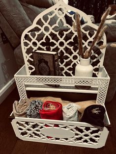 a white shelf with hats and other items in it on a wooden floor next to a couch