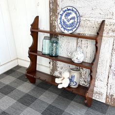 an old wooden shelf with jars and vases on it next to a white wall