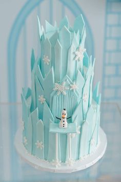 there is a frosted cake that looks like a castle with snowmen on it