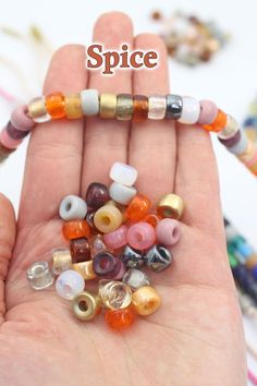 a hand holding several different colored beads in it's palm with the words spice written above them