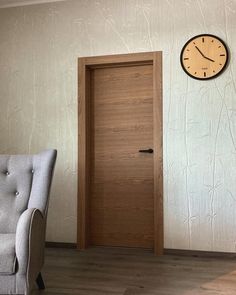 a chair sitting in front of a door with a clock on the wall