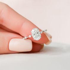 a woman's hand holding an engagement ring with a diamond in the middle, on top of her finger