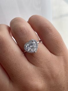 a woman's hand with a diamond ring on top of her finger and an oval shaped diamond in the middle