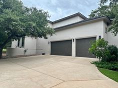 a house with two garages and trees in the front yard