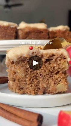 a piece of cake sitting on top of a white plate next to apples and cinnamon sticks