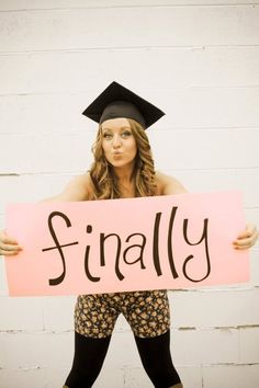 a woman holding a sign that says finally in front of her face and wearing a graduation cap