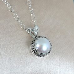 This classic and timeless pearl pendant evokes the romantic style of the Edwardian era with a glowing pearl set within an intricately detailed sterling silver setting. A creamy white cultured freshwater button pearl, approximately 8-8.5mm in diameter is set in a hand-wrought heart-crown setting of recycled sterling silver that has been lightly oxidized to showcase the setting's detail. The pearl pendant glides freely on a slim sterling silver cable chain in your choice of 18 or 20-inch necklace Silver Pearl Necklace With Pendant, Elegant Silver Pearl Necklace For Gift, Elegant Round Cabochon Necklaces, Timeless Silver Pearl Necklace For Wedding, Elegant Silver Pearl Necklace Gift, Elegant Oval Pearl Necklace For Gift, Elegant Wedding Necklace With Cabochon, Elegant Pearl Necklace With Intricate Design, Silver Pearl Necklace With Pendant For Anniversary