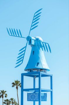 a blue windmill with palm trees in the background