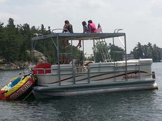 three people are standing on the back of a pontoon boat