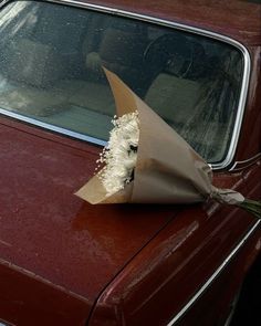 a bouquet of flowers is placed on the hood of a red car in front of a window