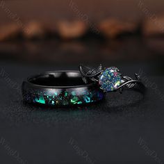 two rings with green and blue designs on them sitting on top of a black surface