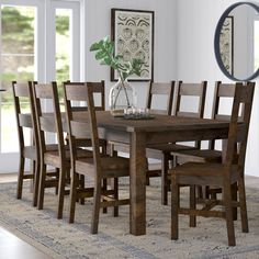 a dining room table and chairs in front of a window with a rug on the floor