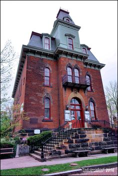 an old red brick building with stairs leading up to the front door and second story