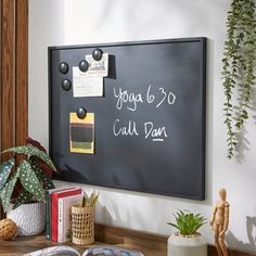 a blackboard with writing on it next to potted plants and other office supplies