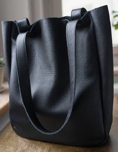 "A large minimal bag on shoulder and hand. Made of black genuine, high quality leather. Inside without lining. Close with two snaps in old gold. Dimensions: Width 32 cm (12,6 \"), Height 38 cm (15\"), depth about 11 cm (4,3\") shoulder straps 65 cm ( 25,5\") Standard delivery time: European union: 4 - 10 days Europe (not EU): 7 - 14 days U.S.A., Canada: 10 - 20 days Australia, South America, Asia, India, North Africa: 1 - 3 weeks We send all items with priority air mail and tracking number." Minimalist Smooth Grain Shoulder Bag For Shopping, Minimalist Leather Bucket Bag With Large Capacity, Minimalist Double Handle Shoulder Bag With Leather Lining, Minimalist Leather Hobo Bag Tote, Simple Leather Shopping Bags, Minimalist Smooth Grain Tote Shoulder Bag, Simple Solid Leather Shoulder Bag, Simple Rectangular Leather Shoulder Bag, Minimalist Textured Leather Shoulder Bag