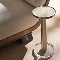 a glass table sitting on top of a floor next to a couch with a chair in the background