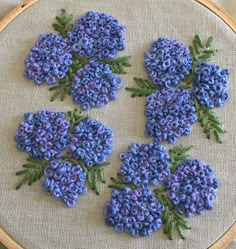 a close up of a cross stitch pattern with blue flowers