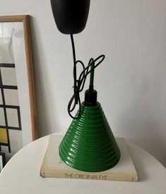 a green lamp sitting on top of a white table next to a framed picture and a book