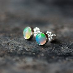 Beautiful, iridescent Ethiopian opal gems are the stars of these elegant earrings. Set entirely in sterling silver, the genuine opals measure 6mm in diameter--these are not manmade or simulated opals. Each real opal is entirely unique, with its own play of color and light. I match the two opals so they compliment each other, but they will never be identical. These are real, natural opal gemstones, not manmade or fake opals. The studs come with large, matching sterling silver push backs. **opals Silver Opal Earrings For Anniversary, Anniversary Silver Opal Earrings, Iridescent Opal Jewelry For Anniversary, Hypoallergenic Sterling Silver Iridescent Jewelry, Hypoallergenic Iridescent Sterling Silver Jewelry, Opal Gemstone Earrings For Anniversary, Iridescent Round Opal Jewelry, Iridescent Opal Round Jewelry, Iridescent Opal Jewelry