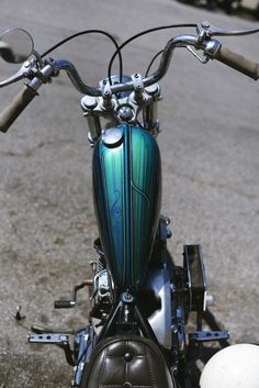 a green and black motorcycle parked on top of a cement road next to a white ball