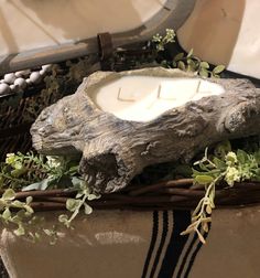 a candle in a wicker basket with greenery on the bottom and an animal's head