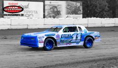 a blue and white truck driving down a dirt track