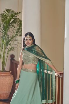 This 3-piece set features a green Titan Silk lehenga choli with 10 meters of flair and a Butterfly Net dupatta. It is standard cancan and canvas attached. The entire set is detailed with dori, mirror, zari and sequins embroidery. The blouse is sleeveless, round necked with back dori and tassels, and measures 0.8 meter. The lehenga is floor-length and flared. Dry-cleaning is recommended for this set. Customizations are available upon checkout; simply add your measurements in the “Order Notes” box