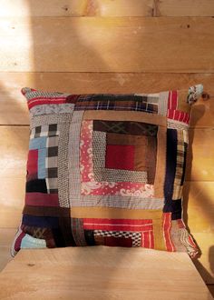 a cushion made out of patchwork on top of a wooden floor next to a wall