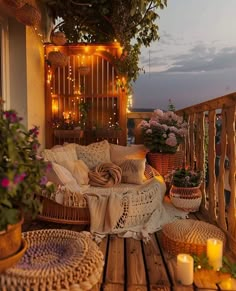 a balcony decorated with wicker furniture and flowers on the table, candles lite up in the background