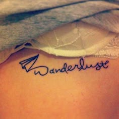 a woman with a tattoo on her back saying wanderlust in cursive writing