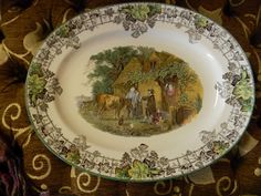 a plate with an image of people and animals painted on the side, sitting on a table