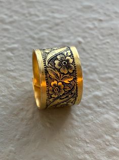 a yellow and black ring with flowers on it sitting on a white surface next to a wall