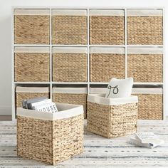 two storage baskets sitting next to each other on top of a rug in front of a wall