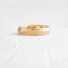 a yellow gold wedding band on top of a white sheet with the word love written in it